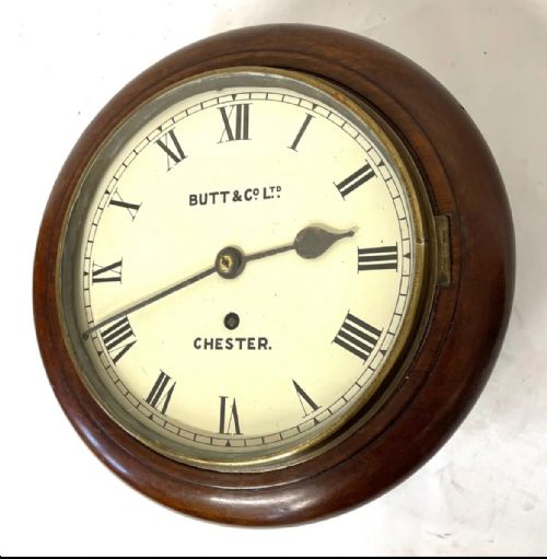 fig 2. A circular mahogany wall clock with an cream dial, black Roman numerals, steel spade hands, and a brass bezel inscribed with Butt and Co Ltd Chester.