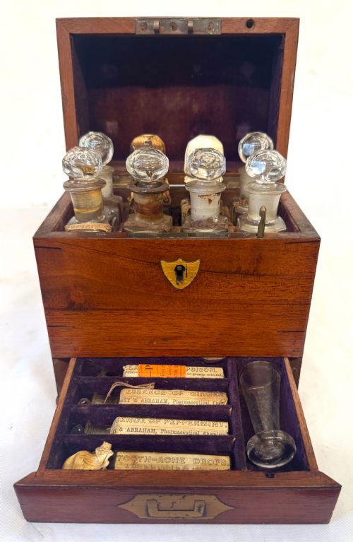 fig 1. An antique wooden apothecary box shown open with glass stoppered bottles in top compartments and labelled vials in a velvet-lined lower drawer.