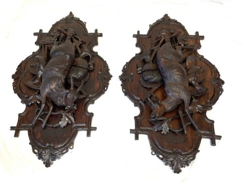 fig 1. A pair of 19th-century carved dark wood wall plaques depicting hunted game, including a chamois and birds framed by oak foliage and hunting gear.
