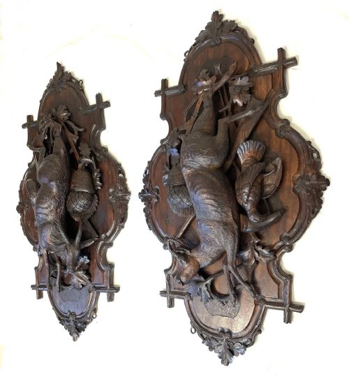 fig 2. A pair of 19th-century carved dark wood wall plaques depicting hunted game, including a chamois and birds framed by oak foliage and hunting gear.