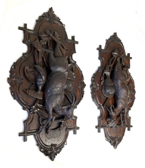 fig 3. A pair of 19th-century carved dark wood wall plaques depicting hunted game, including a chamois and birds framed by oak foliage and hunting gear.