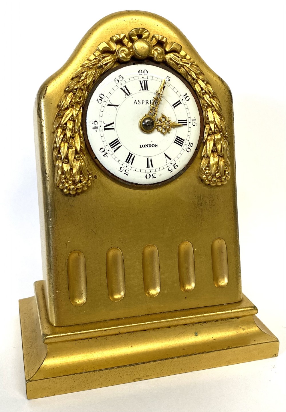 An arched gilt bronze desk clock with carved laurel garland details and a white enamel dial marked Asprey London.