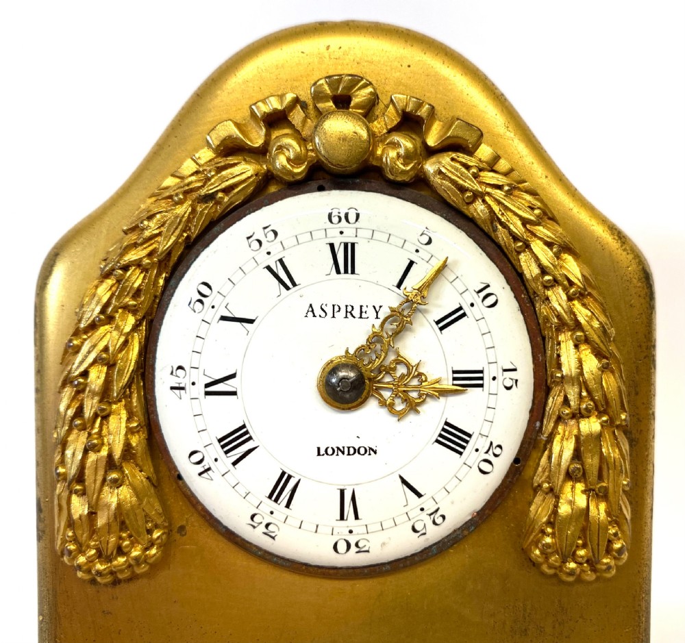 An arched gilt bronze desk clock with carved laurel garland details and a white enamel dial marked Asprey London. View III