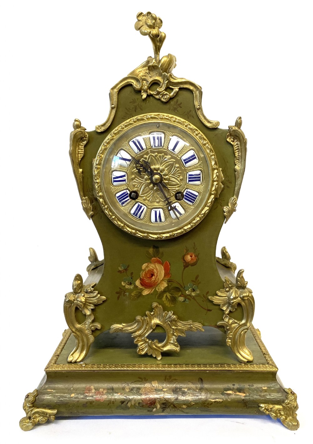 An olive green hand-painted French mantel clock set on a matching plinth stand with gilded bronze ormolu mounts, floral motifs, and a central circular dial with enamel Roman numeral markers.