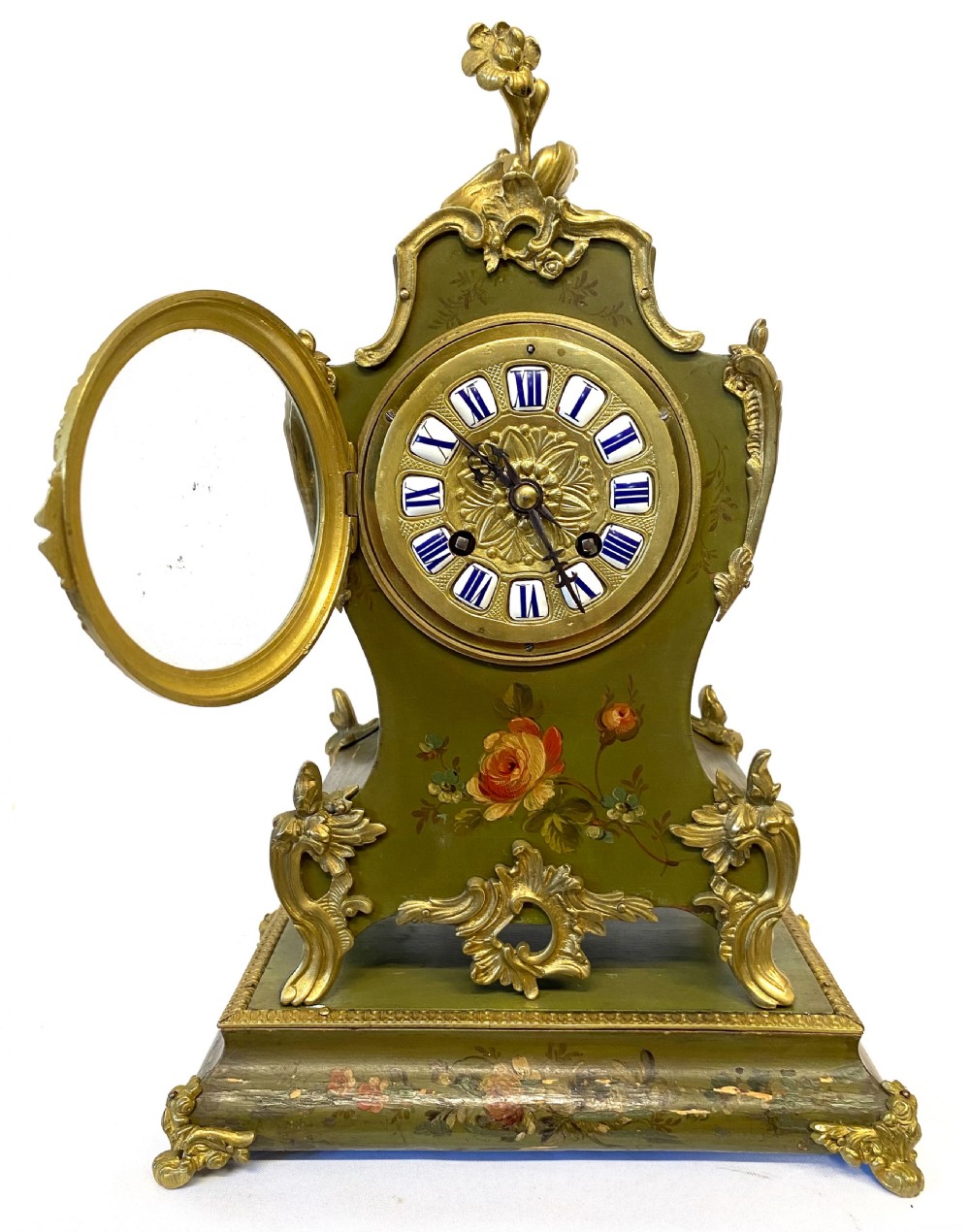 An olive green hand-painted French mantel clock set on a matching plinth stand with gilded bronze ormolu mounts, floral motifs, and a central circular dial with enamel Roman numeral markers. View III