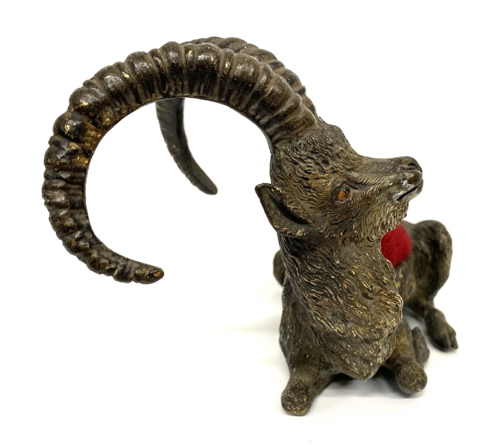 An antique Austrian cold-painted bronze figurine of a recumbent ibex with long curved horns and an integrated red velvet pin cushion set into its back. View VI