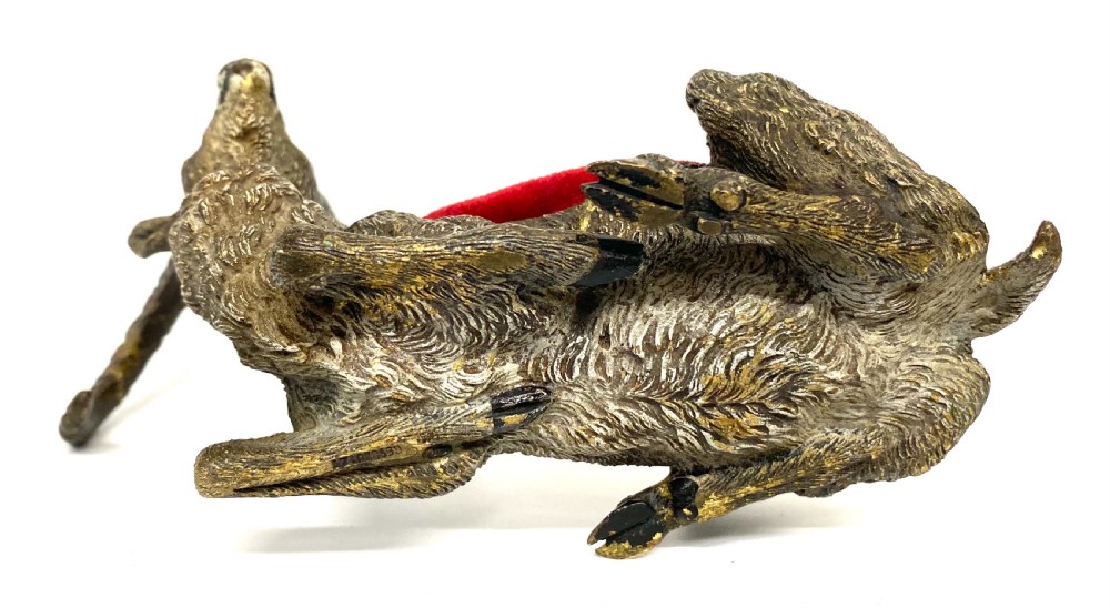 An antique Austrian cold-painted bronze figurine of a recumbent ibex with long curved horns and an integrated red velvet pin cushion set into its back. View IX