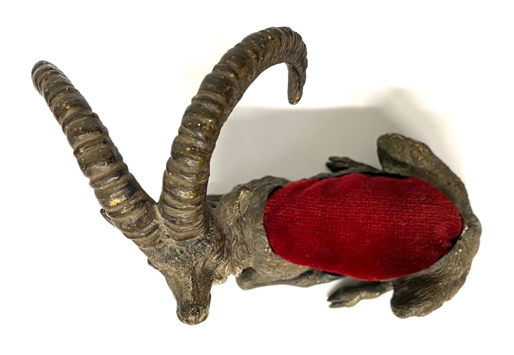An antique Austrian cold-painted bronze figurine of a recumbent ibex with long curved horns and an integrated red velvet pin cushion set into its back. View XI