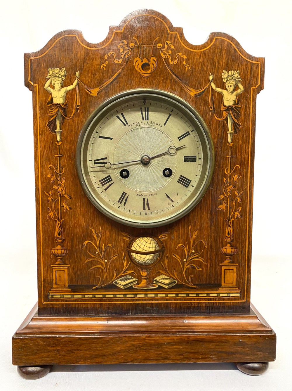 An antique rosewood mantel clock featuring intricate marquetry inlays of figures, swags, and a globe surrounding a circular dial with Roman numerals. View II