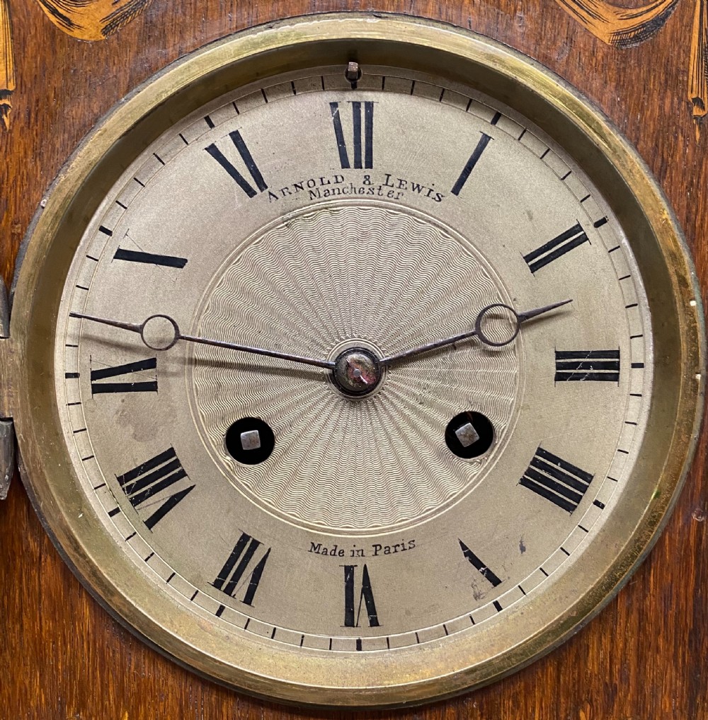 An antique rosewood mantel clock featuring intricate marquetry inlays of figures, swags, and a globe surrounding a circular dial with Roman numerals. View VI