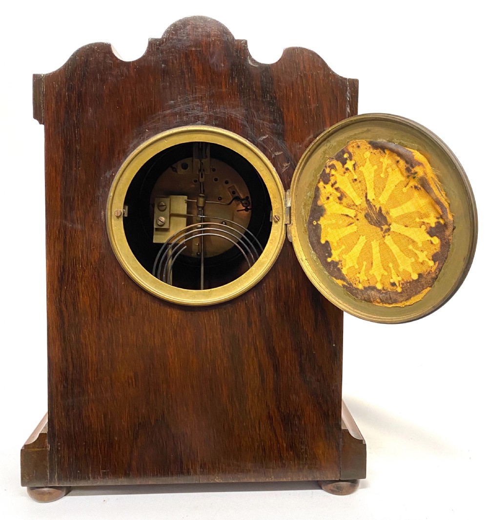 An antique rosewood mantel clock featuring intricate marquetry inlays of figures, swags, and a globe surrounding a circular dial with Roman numerals. View X