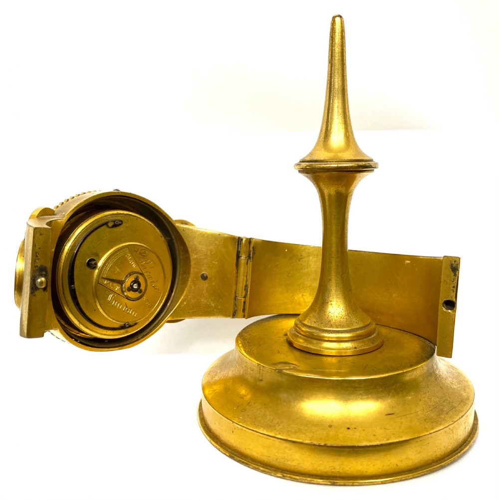 An antique gilt bronze desk clock featuring a white enamel dial with Roman numerals, flanked by blue floral champleve enamel wings and topped with a tapered finial. View VII