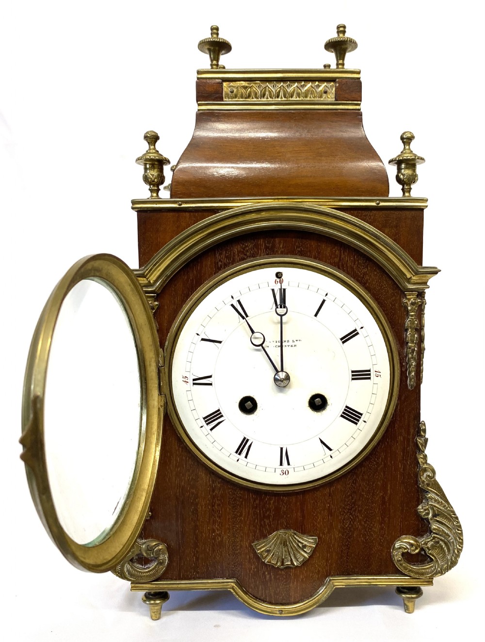A French mahogany mantel clock featuring ornate gilt ormolu mounts, brass finials, and a white circular dial with Roman numerals. View III