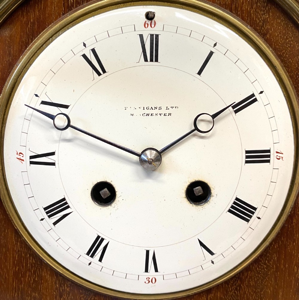 A French mahogany mantel clock featuring ornate gilt ormolu mounts, brass finials, and a white circular dial with Roman numerals. View IV