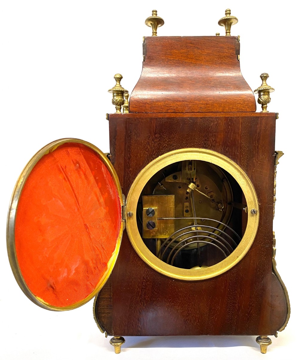 A French mahogany mantel clock featuring ornate gilt ormolu mounts, brass finials, and a white circular dial with Roman numerals. View VIII