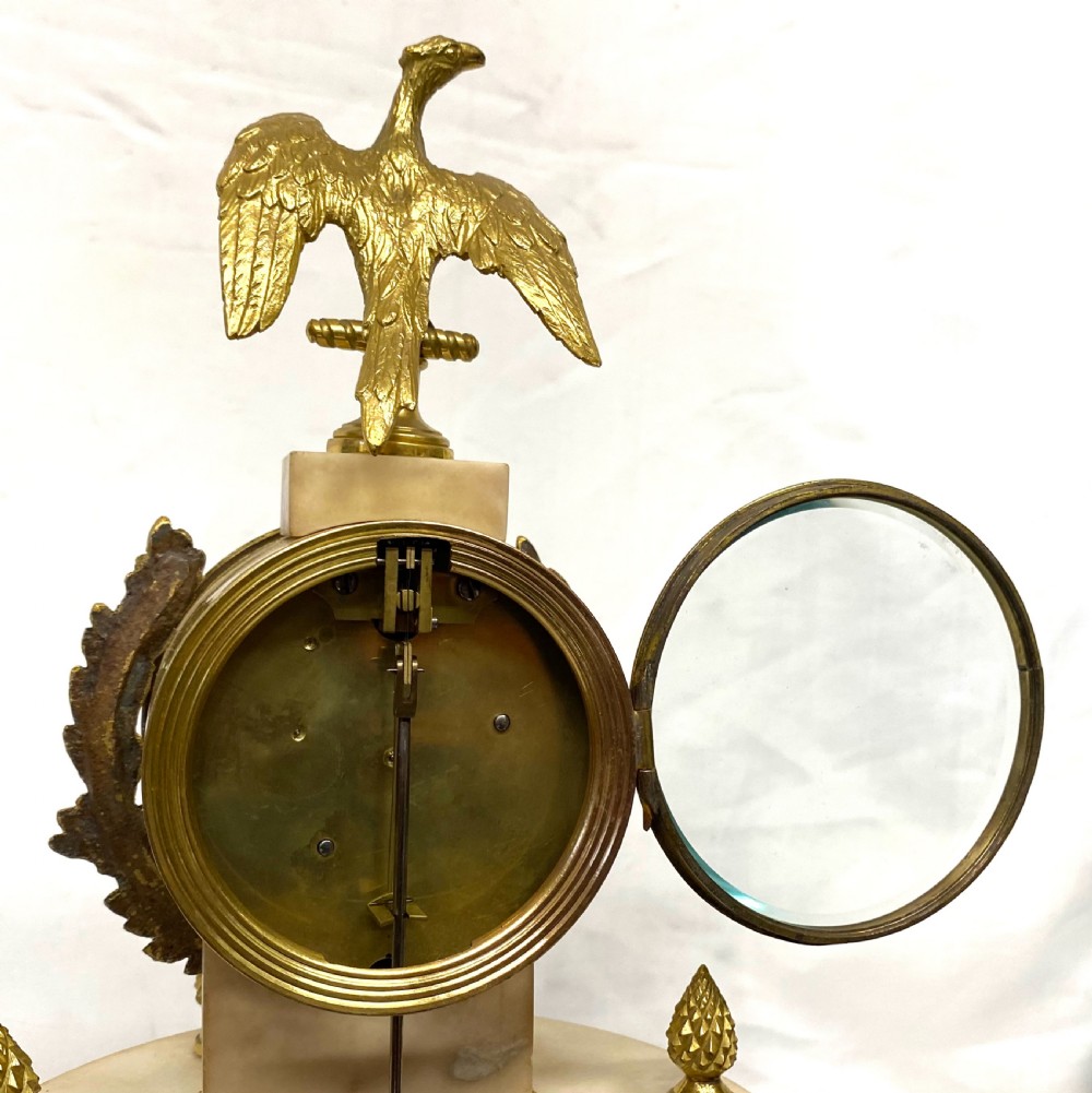 An antique Neoclassical portico clock crafted from white alabaster columns and gilt bronze accents, topped with an eagle finial. View VIII