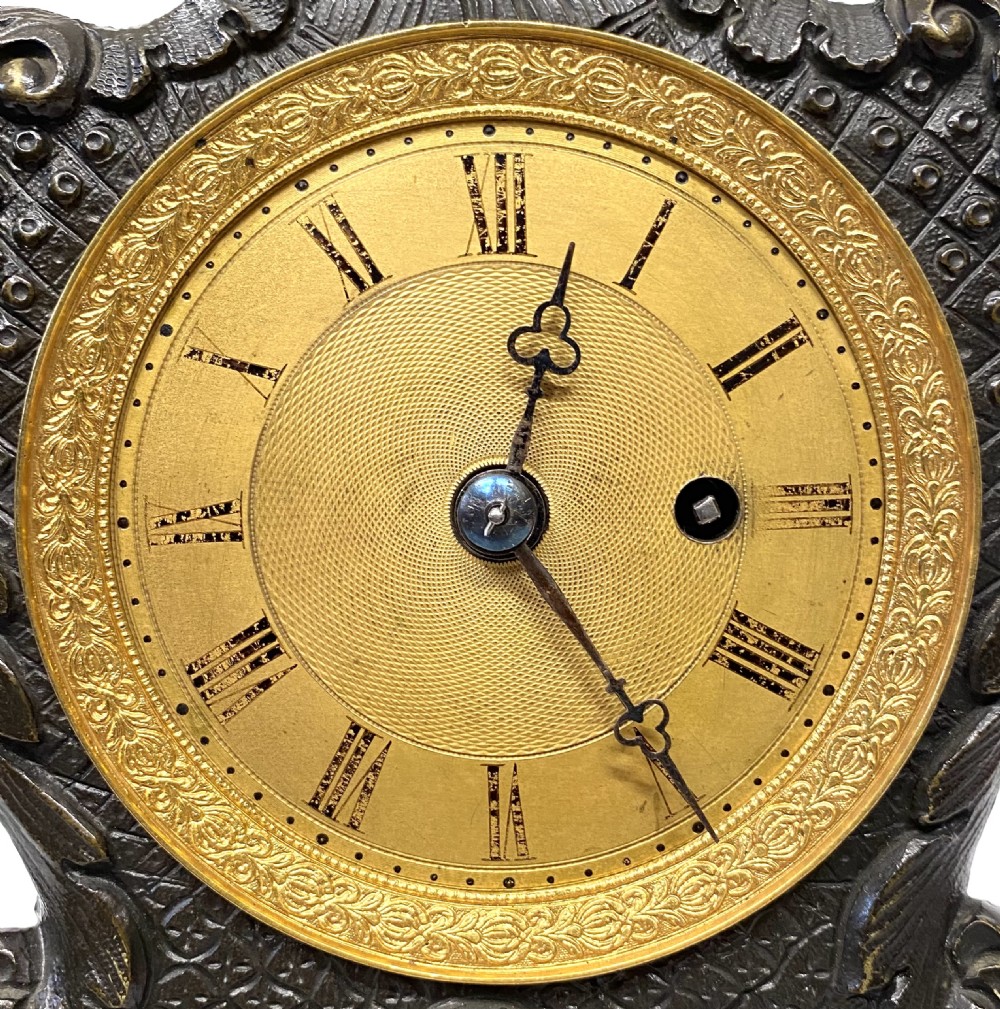 An antique miniature bronze mantel clock featuring Rococo scrollwork, cabriole legs, and an engraved gold-tone brass dial with Roman numerals. View II