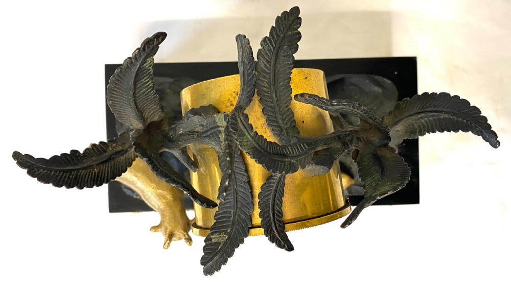 An antique Regency gilt and patinated bronze mantel clock featuring sculpted goats beneath palm trees on a black rectangular base with scrolled gilt feet. View XI