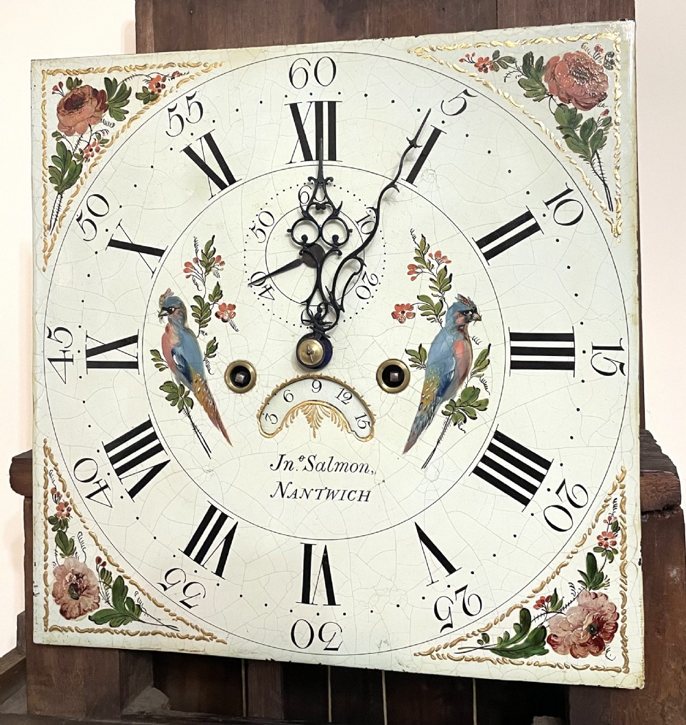 An antique oak and mahogany longcase grandfather clock featuring three brass ball finials, a hand-painted dial face, and fluted column details. View X