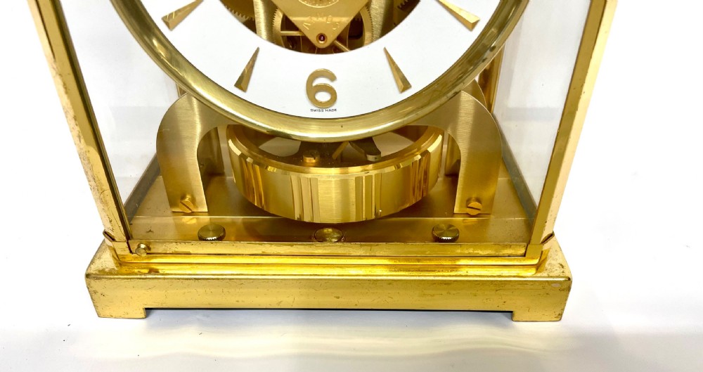 A mid-twentieth-century Jaeger-LeCoultre Atmos clock featuring a rectangular gilt brass frame with glass side panels exposing the mechanical movement and white dial. View V