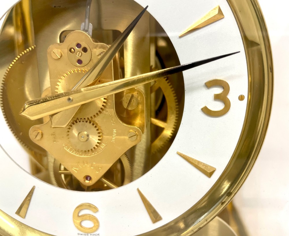 A mid-twentieth-century Jaeger-LeCoultre Atmos clock featuring a rectangular gilt brass frame with glass side panels exposing the mechanical movement and white dial. View VII