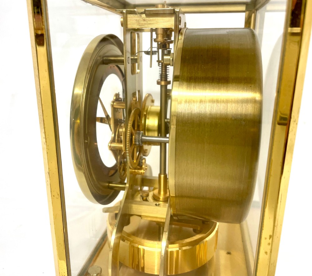 A mid-twentieth-century Jaeger-LeCoultre Atmos clock featuring a rectangular gilt brass frame with glass side panels exposing the mechanical movement and white dial. View XIII