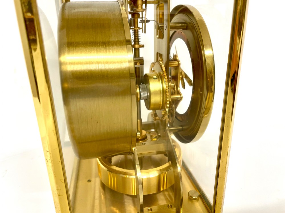 A mid-twentieth-century Jaeger-LeCoultre Atmos clock featuring a rectangular gilt brass frame with glass side panels exposing the mechanical movement and white dial. View XIV