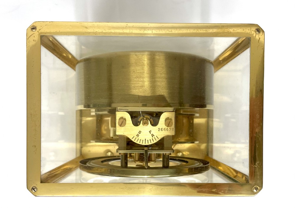 A mid-twentieth-century Jaeger-LeCoultre Atmos clock featuring a rectangular gilt brass frame with glass side panels exposing the mechanical movement and white dial. View XVII