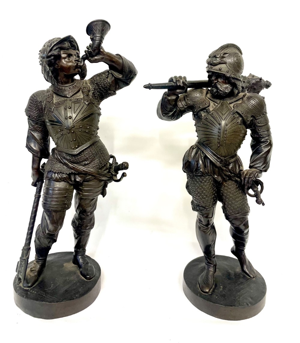 A pair of dark patinated Victorian bronze figures depicting armoured cavalier soldiers standing on circular bases.