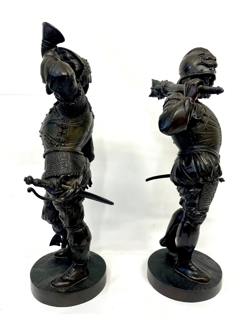 A pair of dark patinated Victorian bronze figures depicting armoured cavalier soldiers standing on circular bases. View V