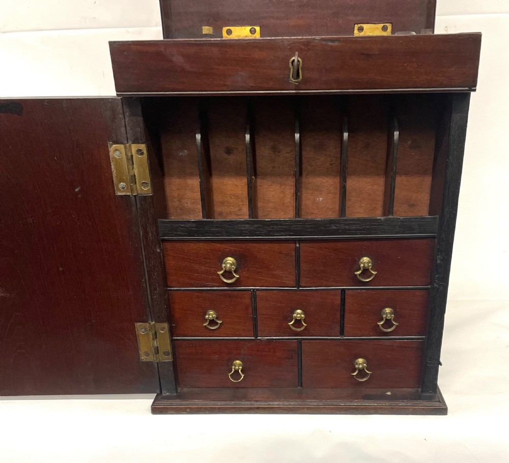 A Georgian dark mahogany apothecary chest with an open hinged lid revealing glass stoppered bottles, a side-hinged door, and interior drawers with brass handles. View VIII