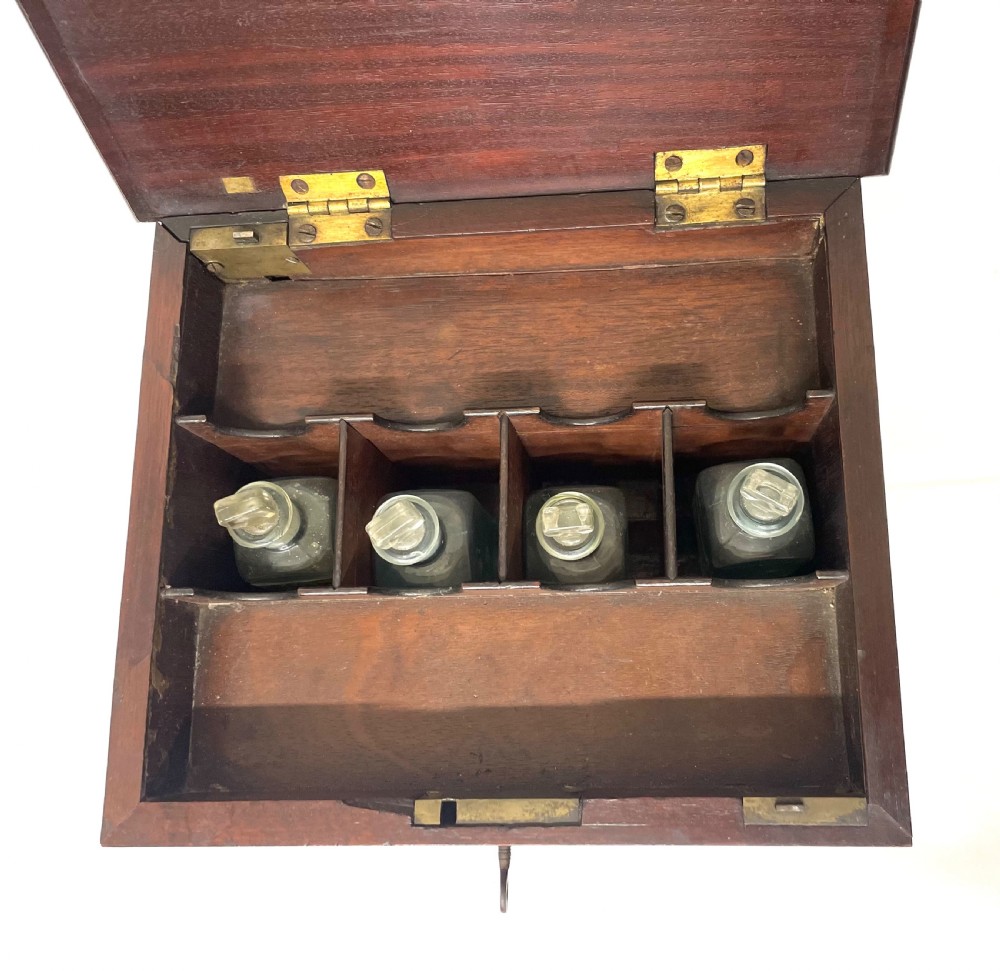 A Georgian dark mahogany apothecary chest with an open hinged lid revealing glass stoppered bottles, a side-hinged door, and interior drawers with brass handles. View XII