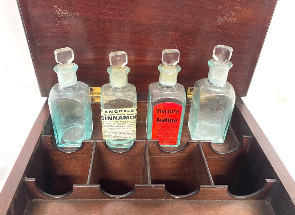 A Georgian dark mahogany apothecary chest with an open hinged lid revealing glass stoppered bottles, a side-hinged door, and interior drawers with brass handles. View XXII