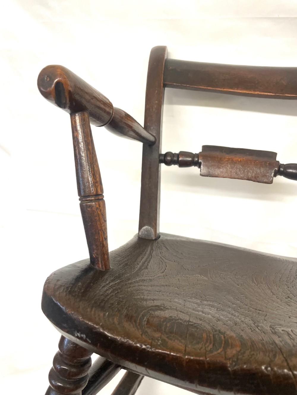 A dark brown wooden childs or dolls rocking armchair featuring turned legs, curved armrests, and smooth wooden rockers. View XIV