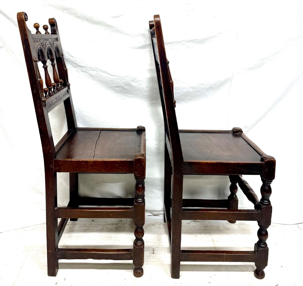 Set of four dark oak dining chairs featuring arcaded carved backs with turned spindles, scroll crestings, and solid plank seats. View VII