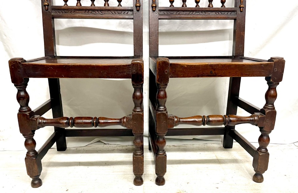 Set of four dark oak dining chairs featuring arcaded carved backs with turned spindles, scroll crestings, and solid plank seats. View XI