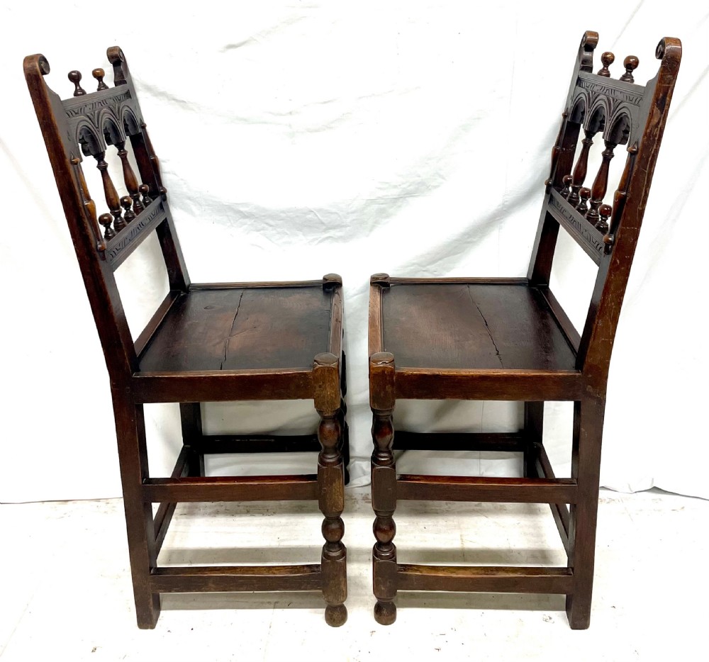 Set of four dark oak dining chairs featuring arcaded carved backs with turned spindles, scroll crestings, and solid plank seats. View XV