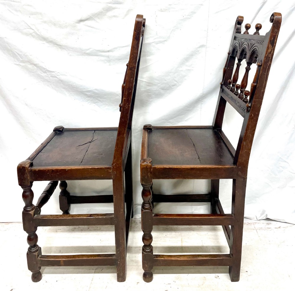 Set of four dark oak dining chairs featuring arcaded carved backs with turned spindles, scroll crestings, and solid plank seats. View XVI