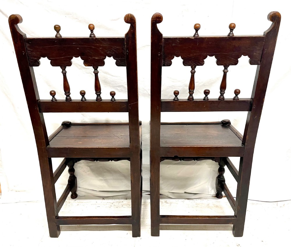 Set of four dark oak dining chairs featuring arcaded carved backs with turned spindles, scroll crestings, and solid plank seats. View XVII