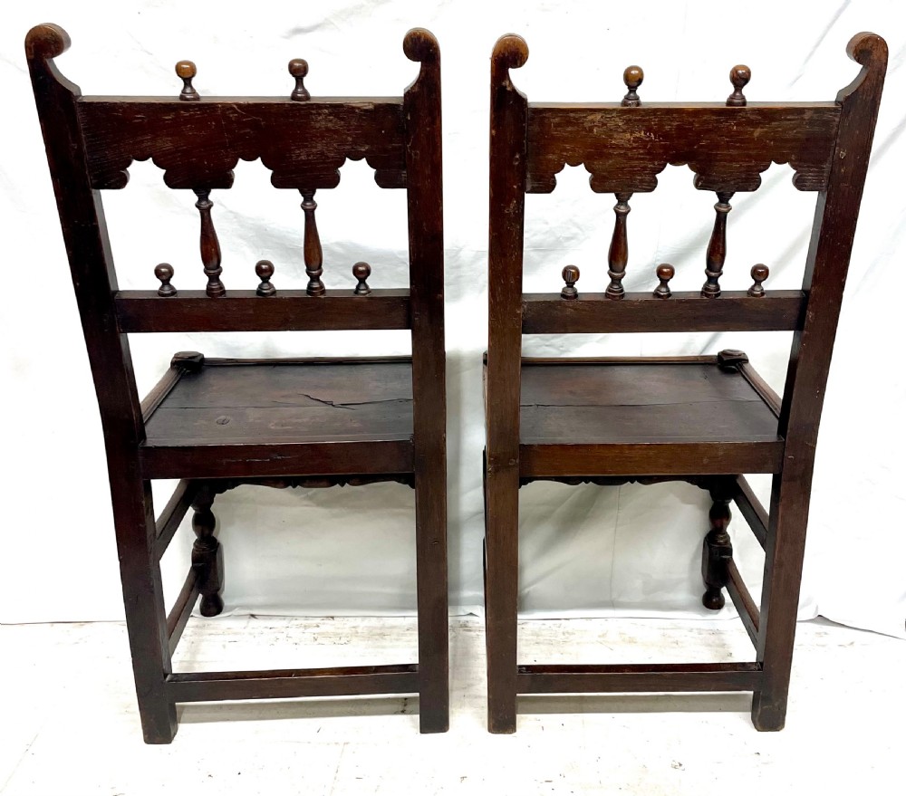 Set of four dark oak dining chairs featuring arcaded carved backs with turned spindles, scroll crestings, and solid plank seats. View XVIII