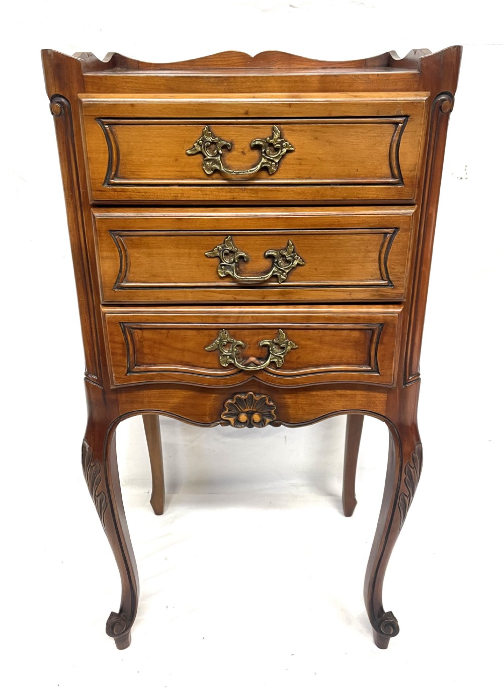 A pair of French satin walnut bedside cabinets featuring three drawers with brass handles, carved shell details on the apron, and slender cabriole legs. View IX