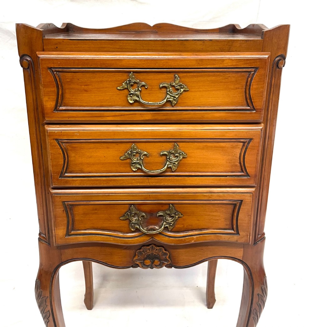 A pair of French satin walnut bedside cabinets featuring three drawers with brass handles, carved shell details on the apron, and slender cabriole legs. View X