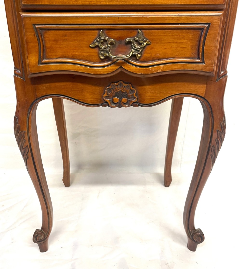 A pair of French satin walnut bedside cabinets featuring three drawers with brass handles, carved shell details on the apron, and slender cabriole legs. View XII