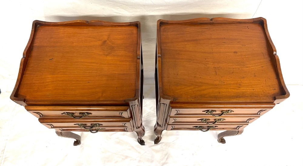 A pair of French satin walnut bedside cabinets featuring three drawers with brass handles, carved shell details on the apron, and slender cabriole legs. View XIII