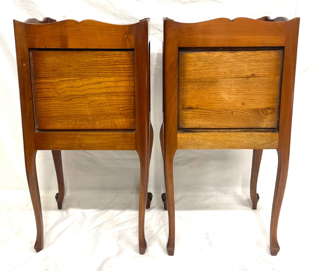 A pair of French satin walnut bedside cabinets featuring three drawers with brass handles, carved shell details on the apron, and slender cabriole legs. View XX