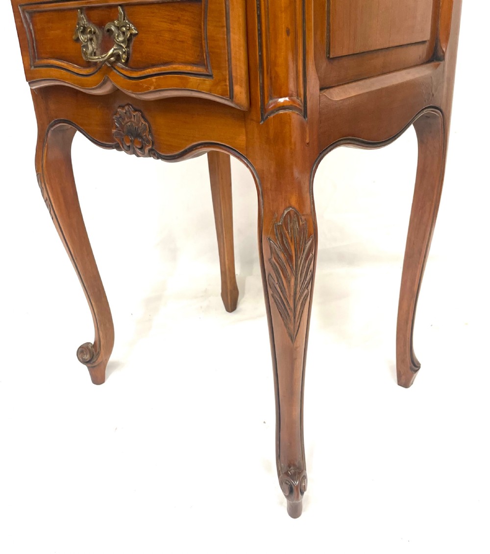 A pair of French satin walnut bedside cabinets featuring three drawers with brass handles, carved shell details on the apron, and slender cabriole legs. View XXI
