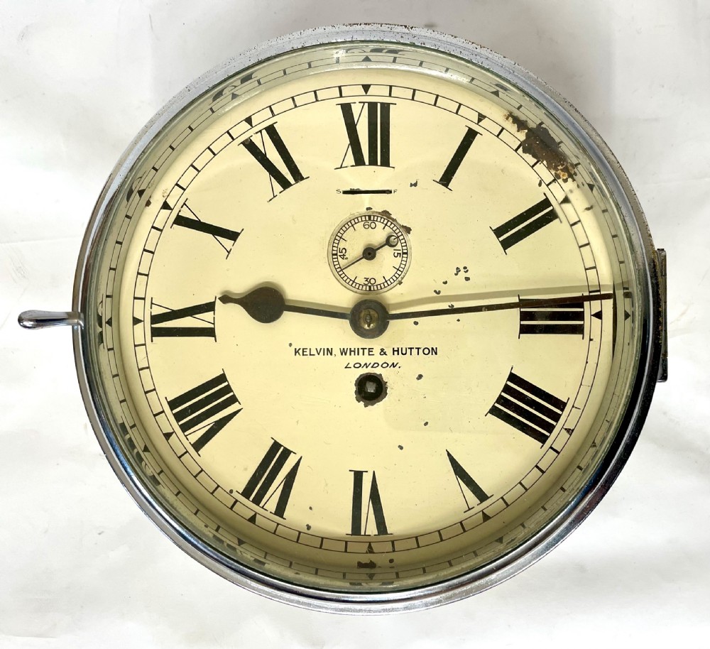 An antique circular nickel-plated brass ships bulkhead clock featuring a cream dial with Roman numerals and a subsidiary seconds dial.