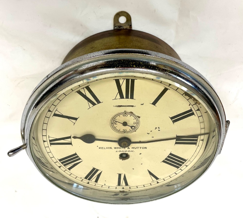 An antique circular nickel-plated brass ships bulkhead clock featuring a cream dial with Roman numerals and a subsidiary seconds dial. View IV