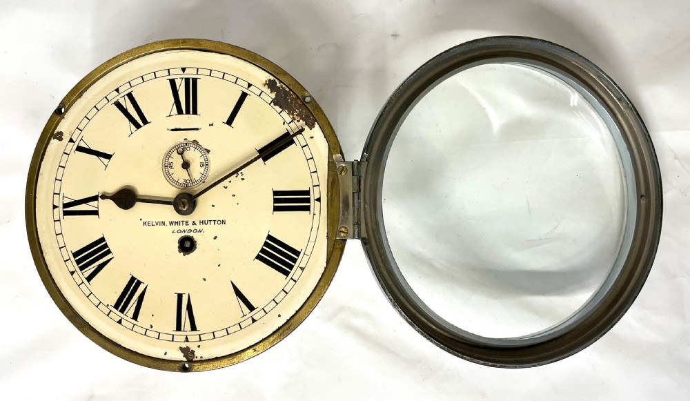An antique circular nickel-plated brass ships bulkhead clock featuring a cream dial with Roman numerals and a subsidiary seconds dial. View VI