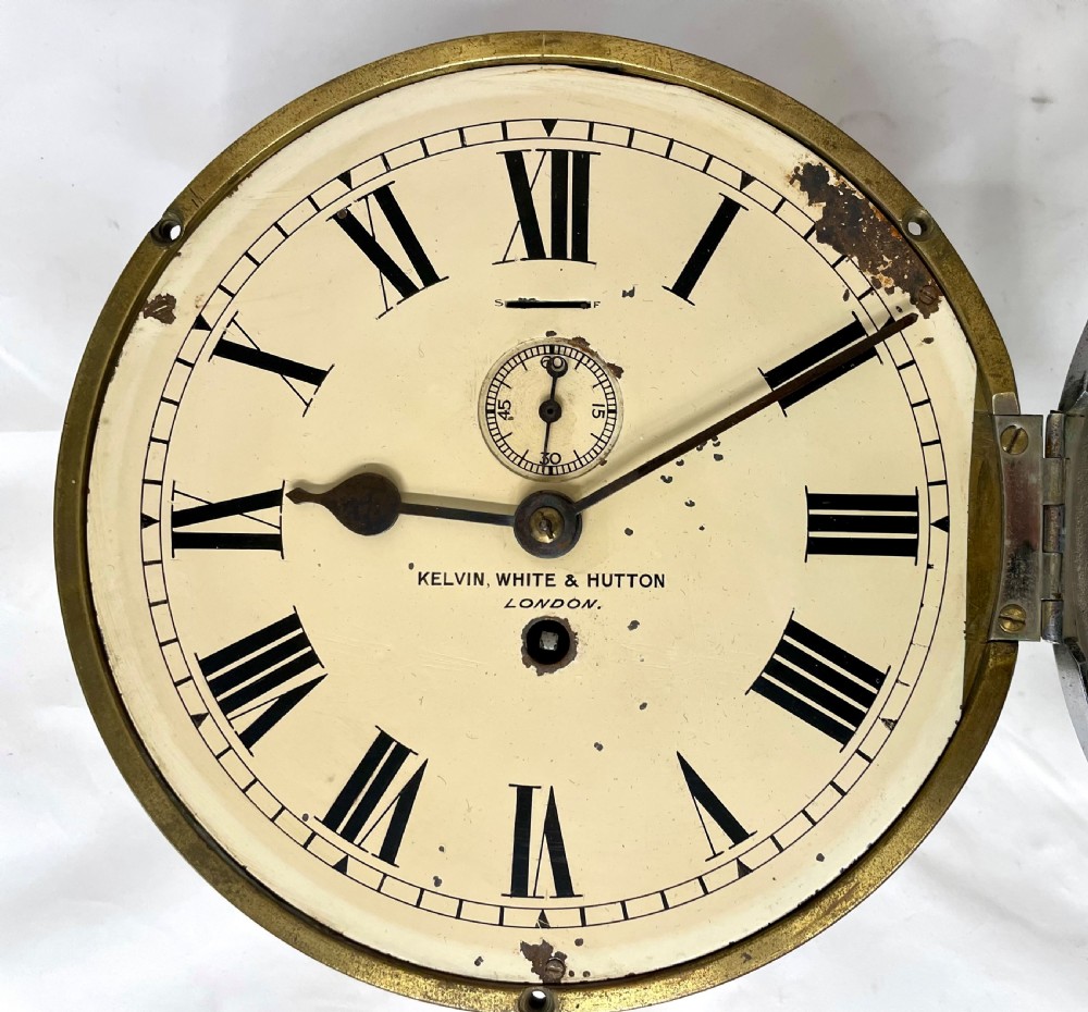 An antique circular nickel-plated brass ships bulkhead clock featuring a cream dial with Roman numerals and a subsidiary seconds dial. View VII